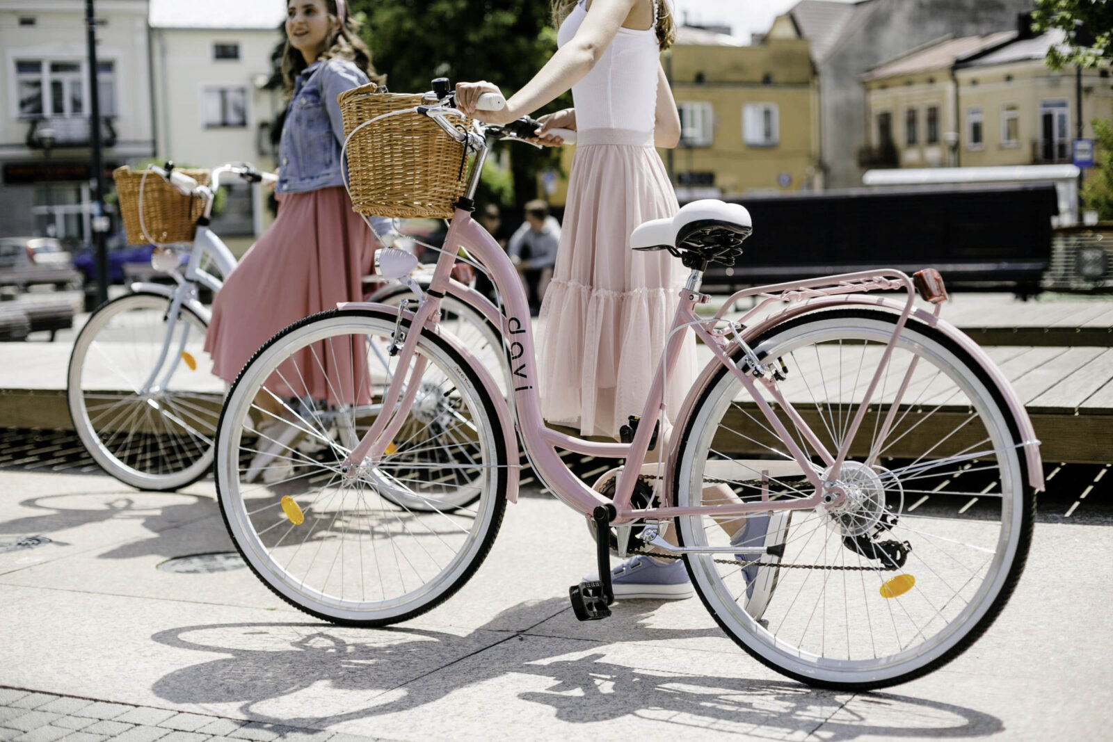 Två kvinnor cyklar med rosa cyklar i stan.