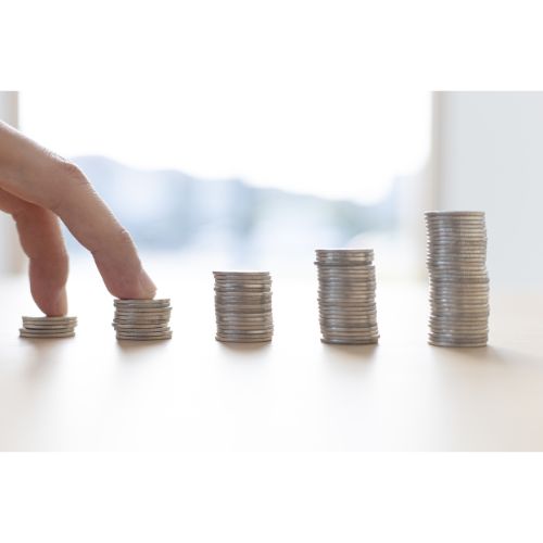 Buntar mynt staplade på bord, hand bläddrar.