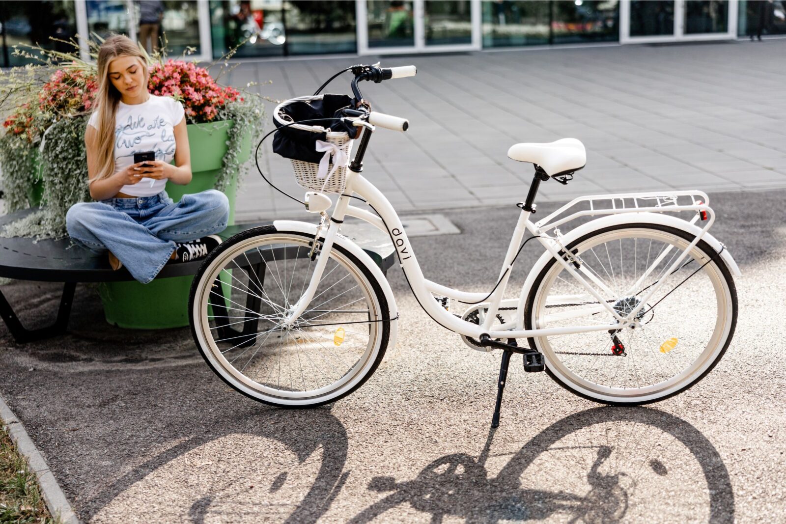 Młoda kobieta siedzi obok białego roweru.