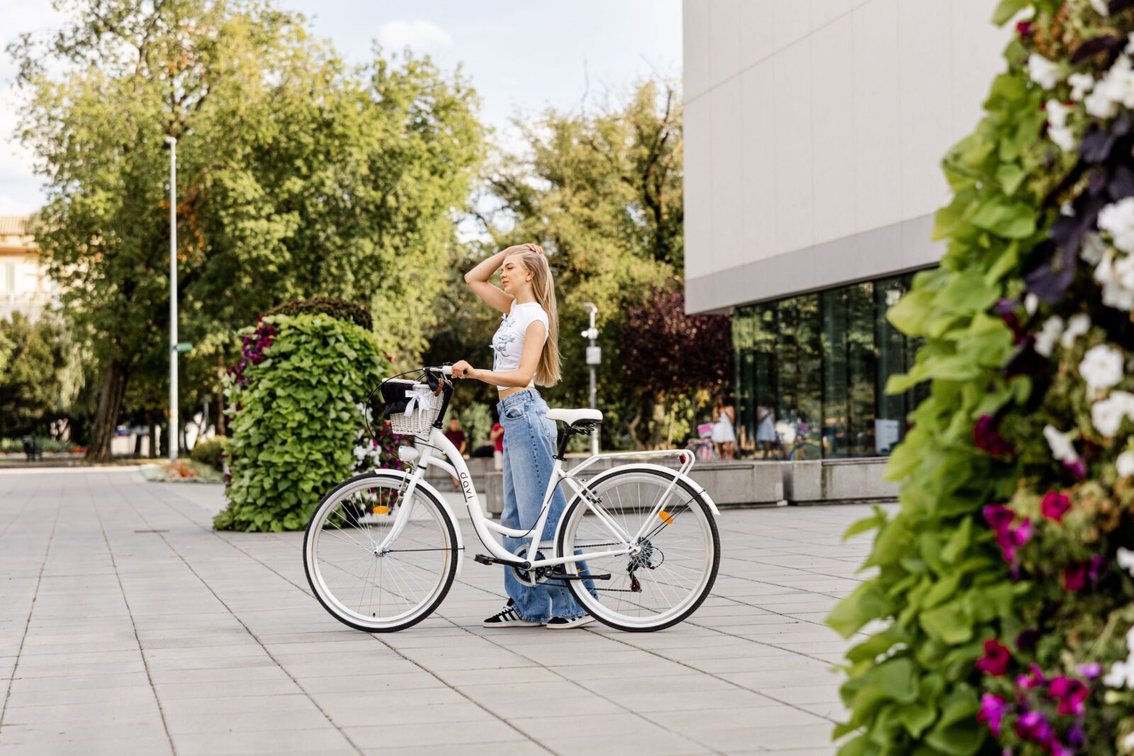 Kobieta pozująca obok białego roweru w parku