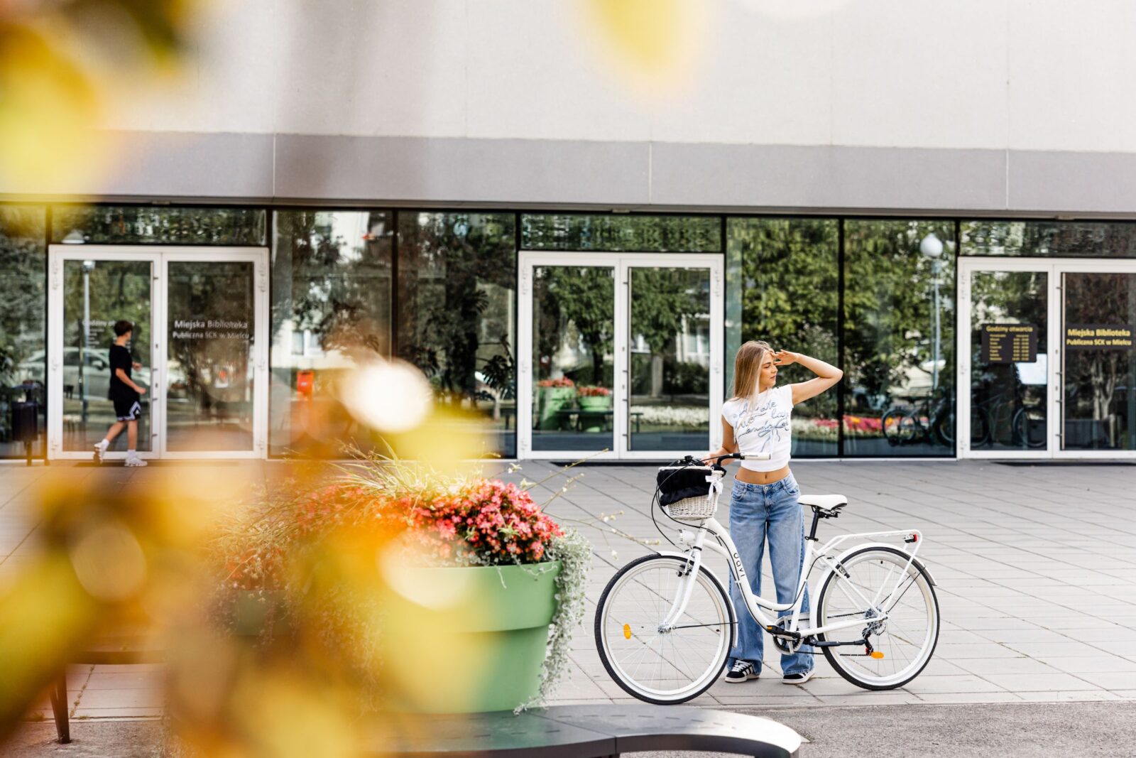 Kobieta z rowerem przed biblioteką