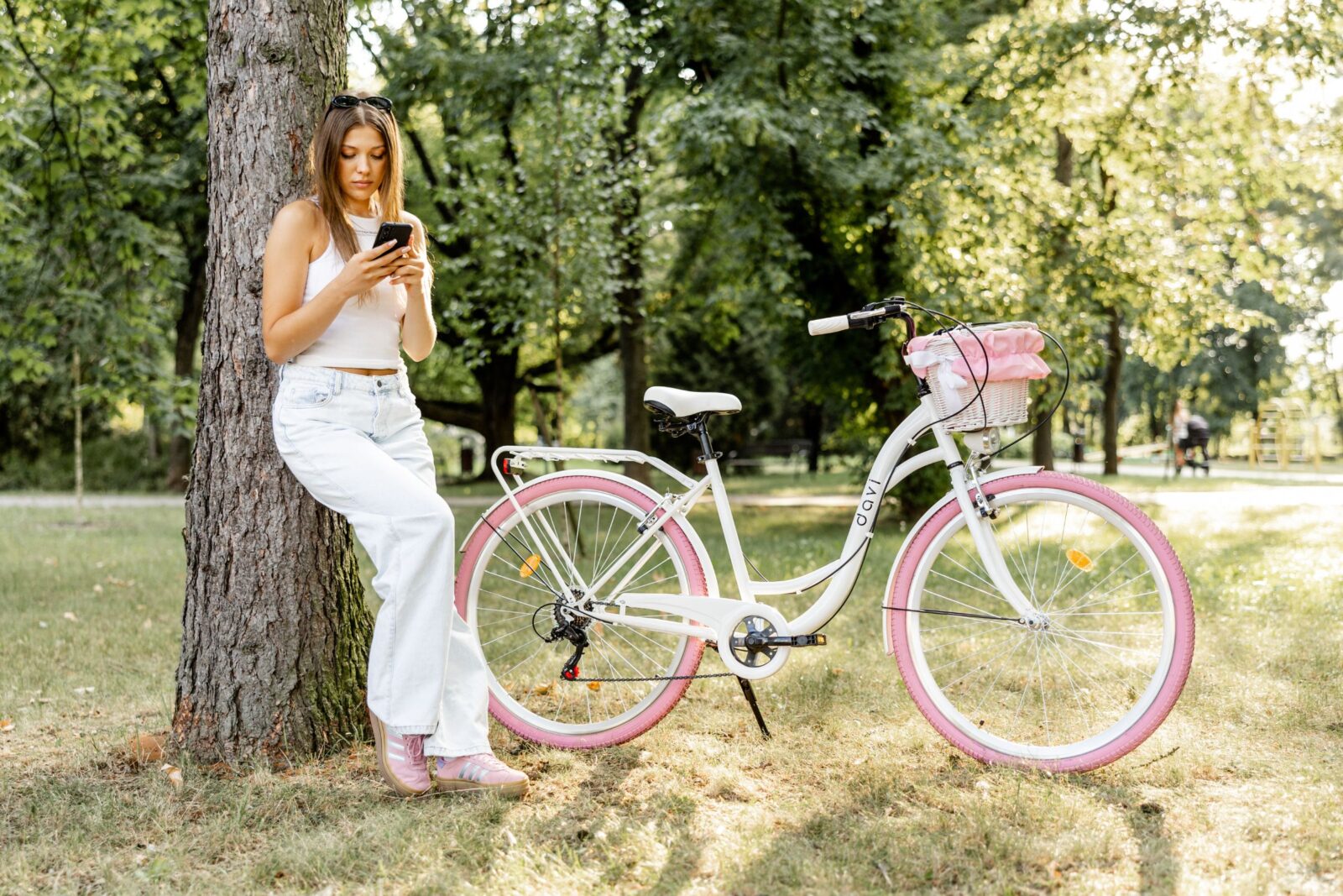 Kobieta siedzi przy rowerze w parku.