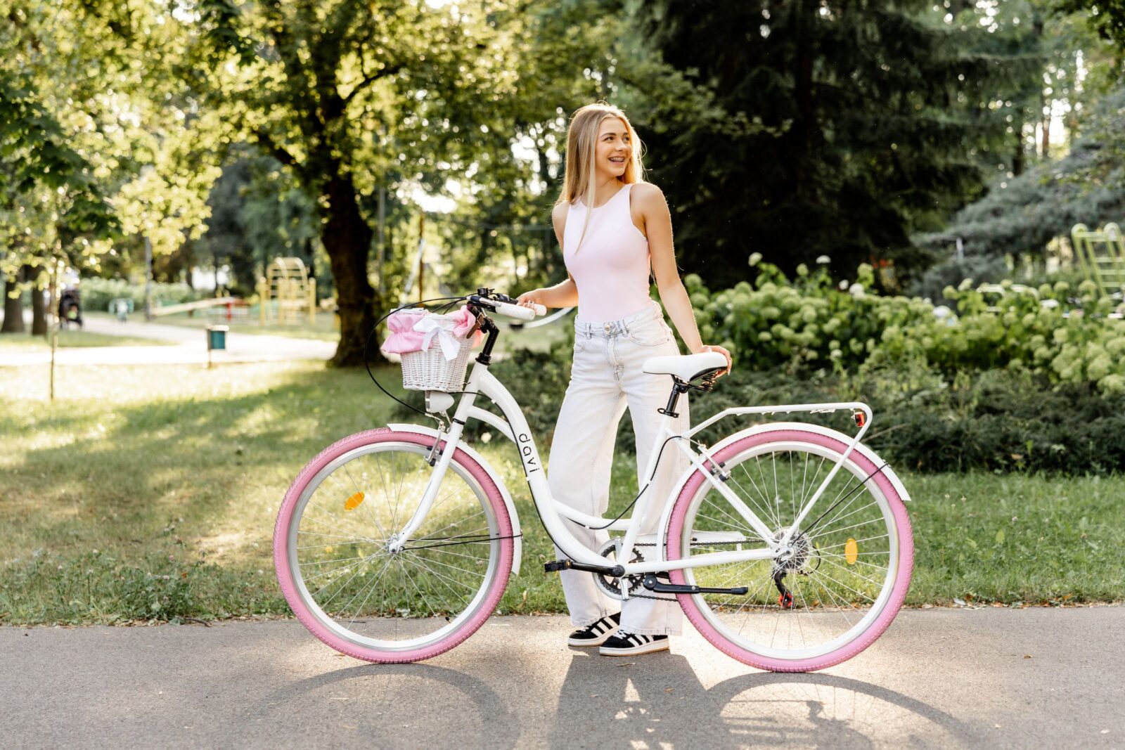 Kobieta w parku z różowym rowerem.