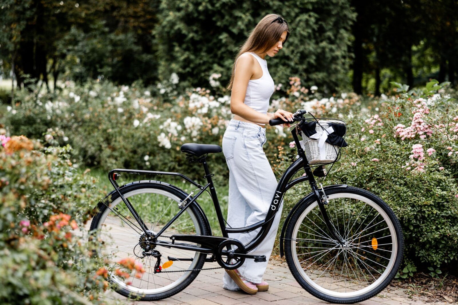 Kobieta obok czarnego roweru w parku