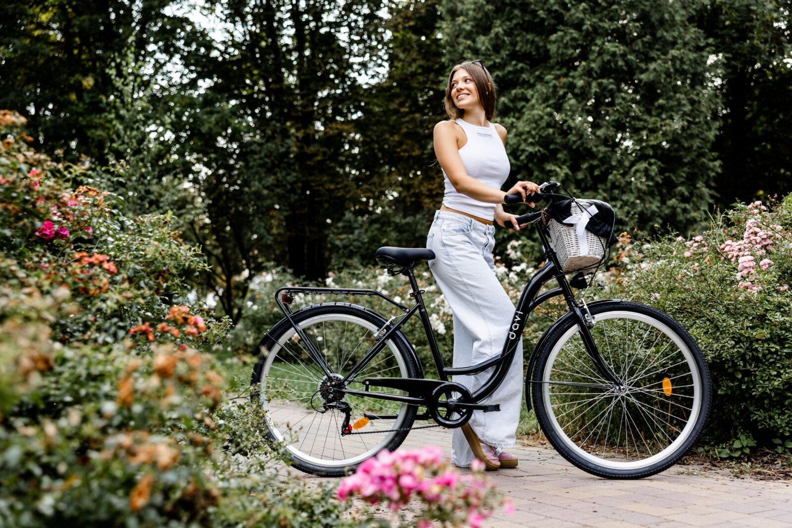 Kobieta z rowerem w kwiecistym ogrodzie.