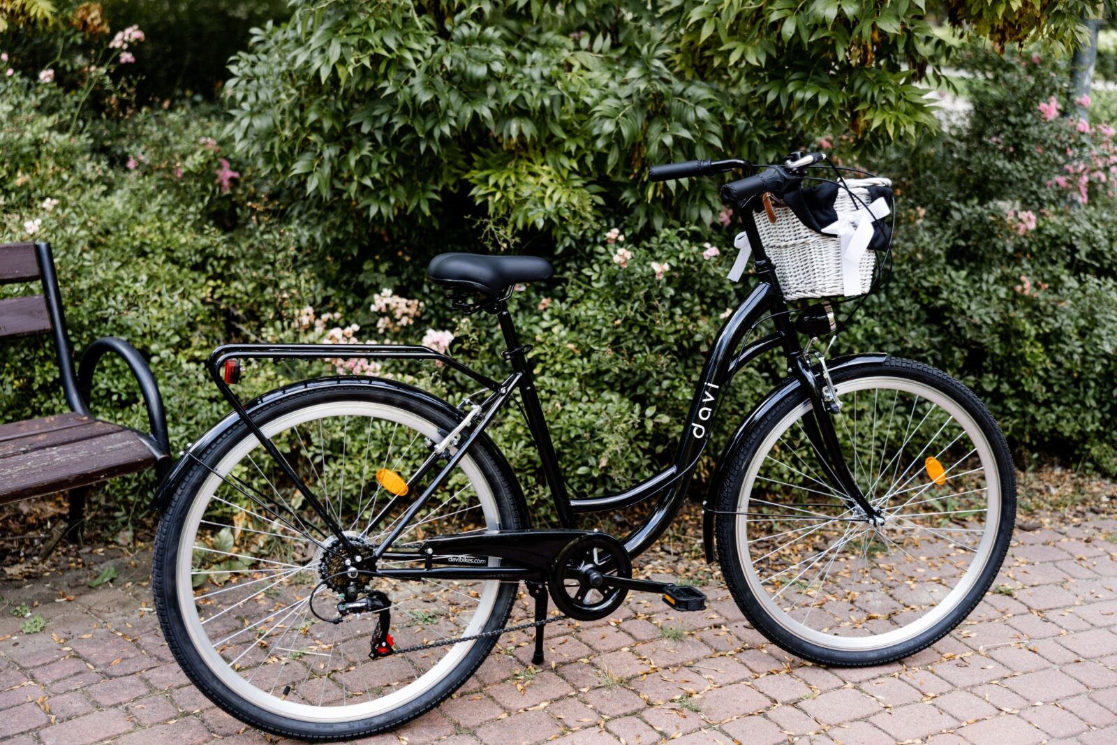 Czarny rower przy ławce w ogrodzie.