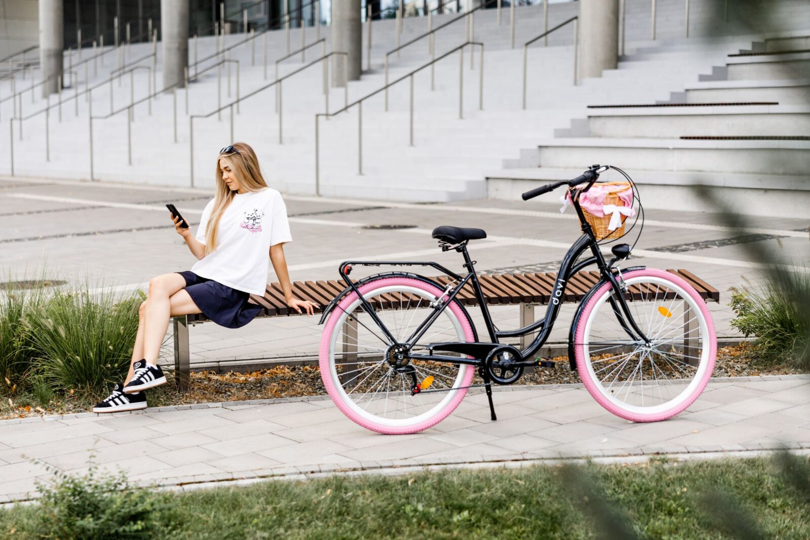 Kobieta z telefonem obok roweru na ławce