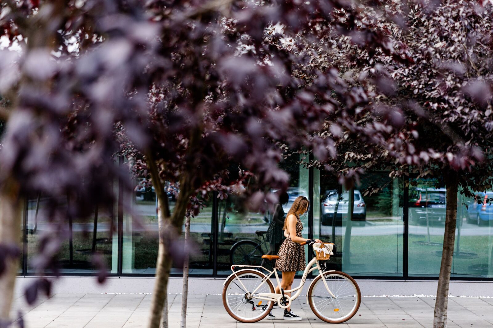 Kobieta w sukience obok roweru w parku