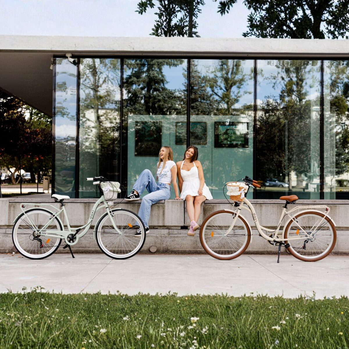 Dwie kobiety siedzą na murku z rowerami.