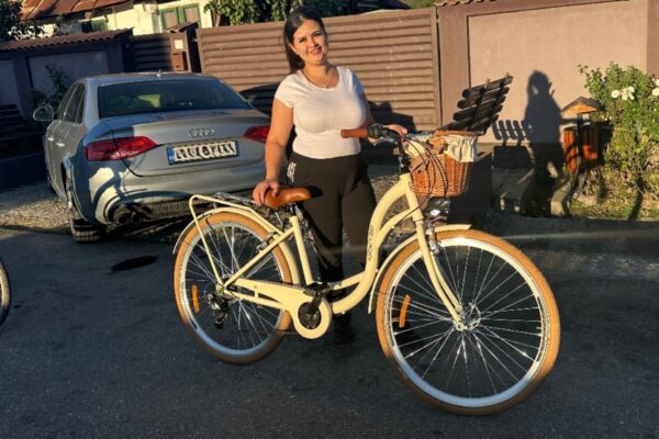 Kobieta z rowerem w słonecznym otoczeniu.